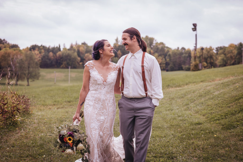 wedding couple walking together with a fall colored bouquet