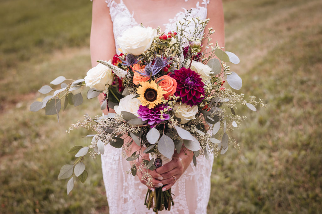 beautiful fall colored wedding bouquet held by a bride in a field