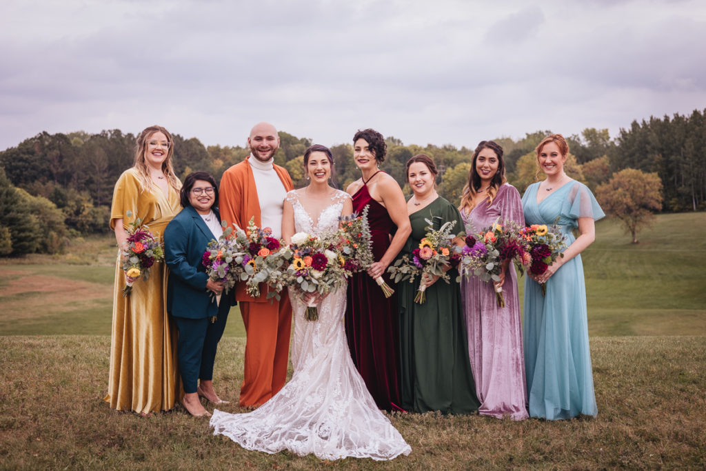 Rainbow themed wedding party in a formal portrait in a field