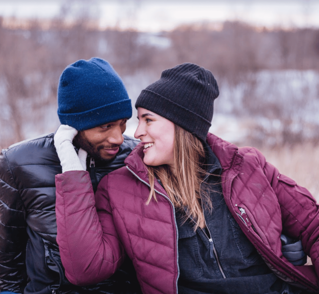 A couple bundled up in winter apparel for their engagement photography session. 