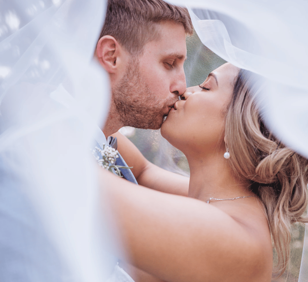 Bride and Groom kissing under a veil at their minnesota wedding. 