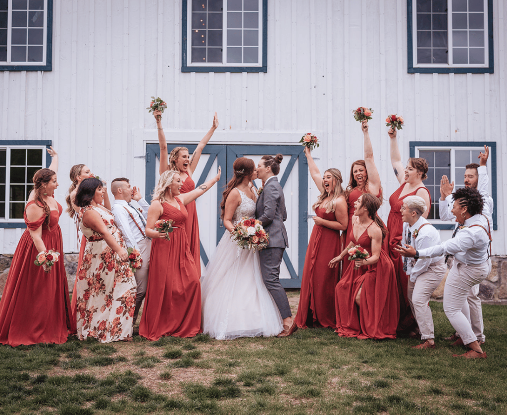 Image of a couple kissing and wedding party is cheering around them for a unique wedding party photo idea. 