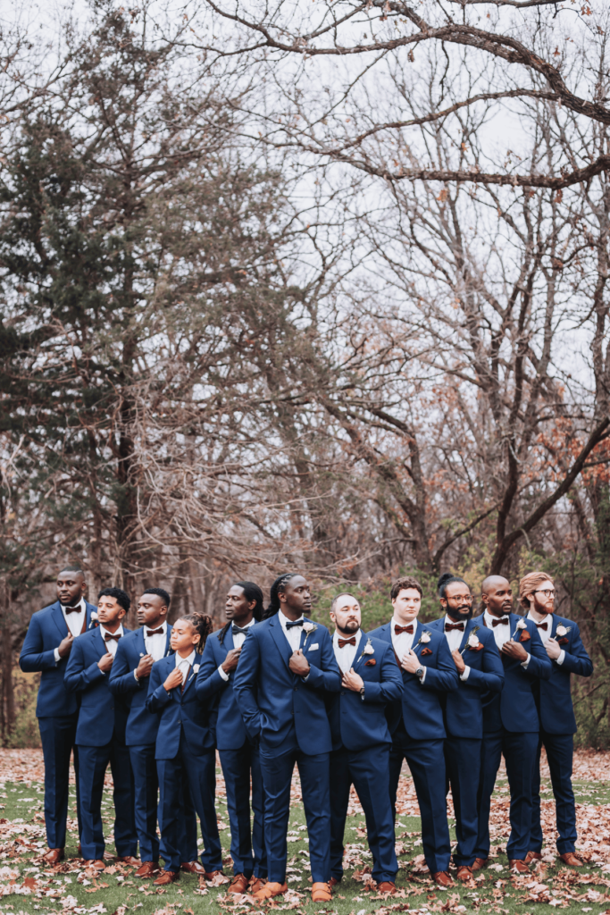Image of large groomsmen party of 10 with groom lined up in flying V formation stance. 