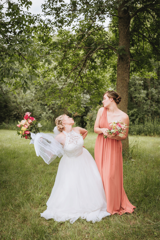 Image of bride and maid of honour sticking out their tongues at each other being silly for wedding photos. 