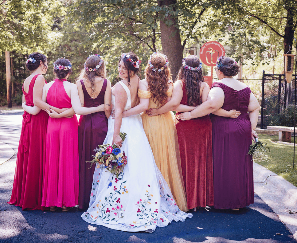 Image of a bridal party looking away from the camera and linking arms while the bride looks back at the camera. 