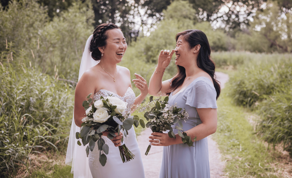 Image of a bride and maid of honour laughing together for a candid wedding photo. 