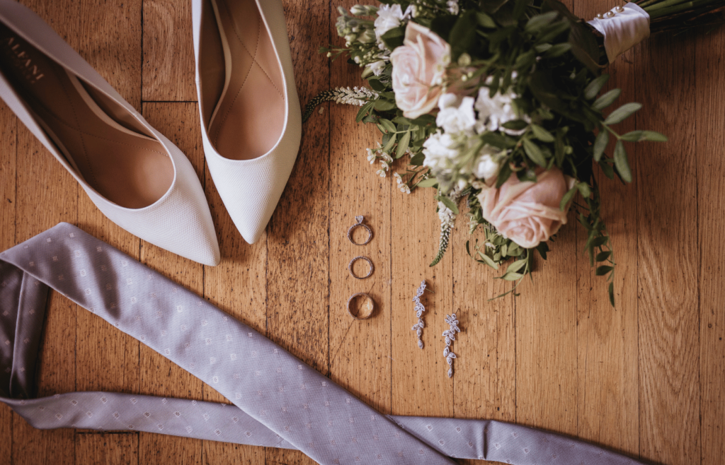 Image of wedding detail photos with a lavender tie, white heels, rings and a bouquet. 