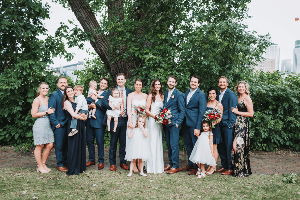 Image of a couples family standing with them on their wedding day. Showing how to start planning for a wedding with thinking about your guest list. 