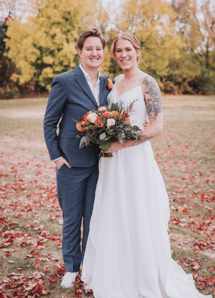 Image of a wedding couple standing outside in the fall smiling at each the camera. This is showing what to do with wedding photos by using a nice photo for thank you wedding cards. 