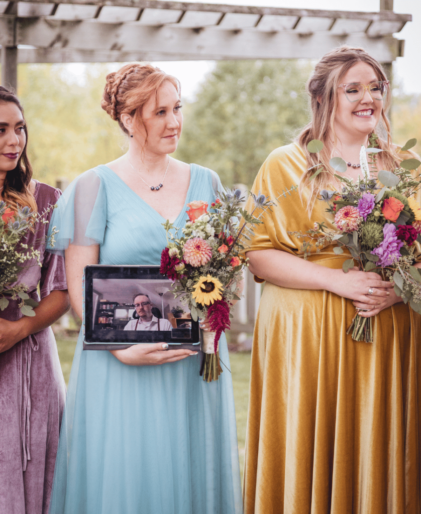Image of a bridesmaid holding onto an Ipad for guests who are joining virtually. 