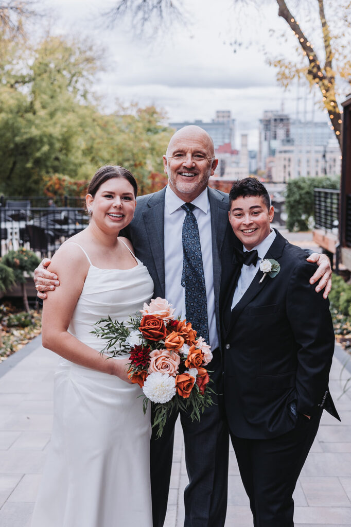An LGBTQ+ couple poses with their officiant in Minneapolis