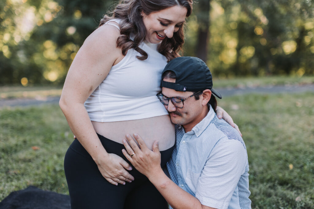 Pregnant woman and her partner post in a Twin Cities park during their maternity photoshoot