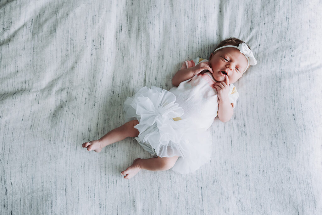 What to dress your newborn in for a newborn session - newborn in a tutu lying on a bed